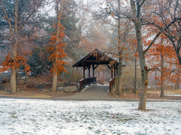 Covered Bridge on a footpath in a park with snow on the ground and Autumn colored leaves on the trees in early winter at Rancho San Rafael Park in Reno Nevada.