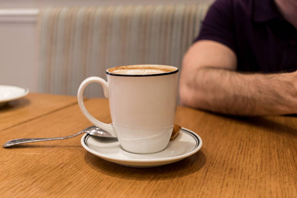 Coffee cup on the wooden table with blurred person on the background
