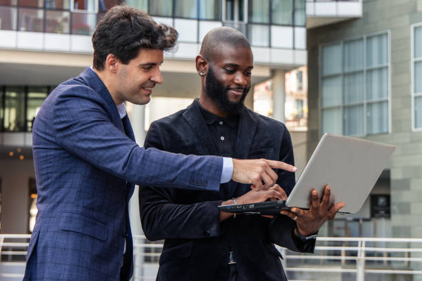 istock African businessman holds laptop while Hispanic colleague points at screen to emphasize data 2162300475