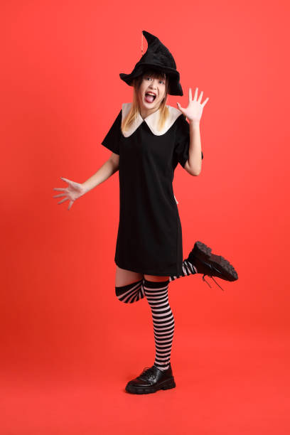 Young asian woman in witch Halloween costume with gesture of yes, excited, celebrating isolated on orange background. October