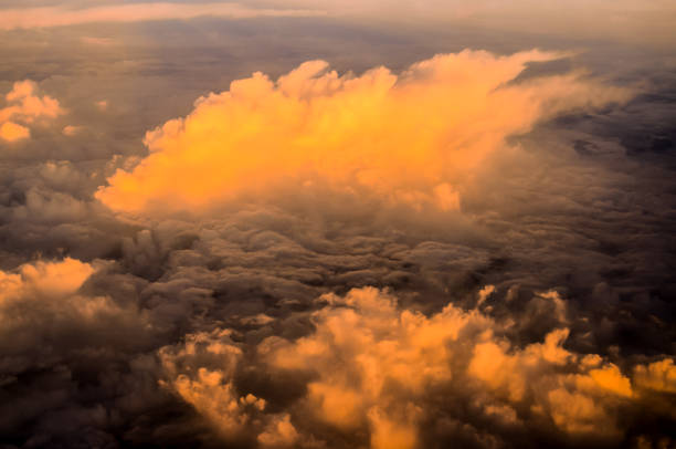 The sky is filled with clouds and the sun is setting. The clouds are orange and the sky is a mix of orange and blue