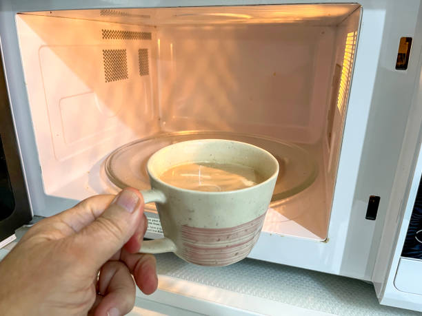 istock Man placing coffee mug in microwave oven 2162308086