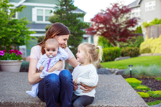 istock Mother and daughters sitting on front steps of house 2162309653