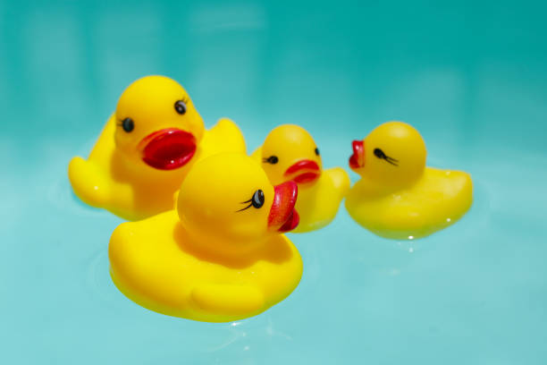 istock Cute yellow rubber ducks floating on blue water 2162313496