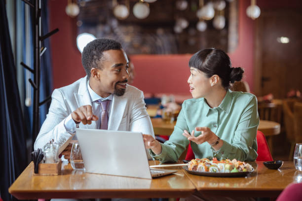 istock Diverse business colleagues enjoying lunch and discussing work in a restaurant 2162314978