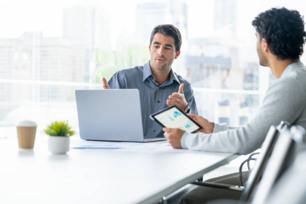 istock Two businessmen working on a digital tablet and laptop computer in the office a board room or meeting room. 2162318389