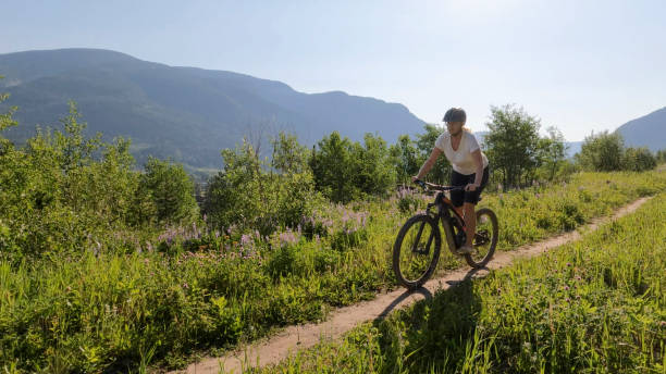 istock Mature woman mountain bikes through meadow 2162318465