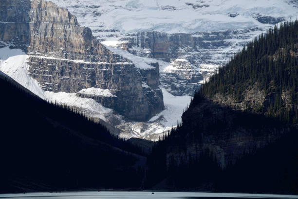 Canoes in the foreground are dwarfed against an extreme close-up of the powerful mountains framing Canada's Lake Louise