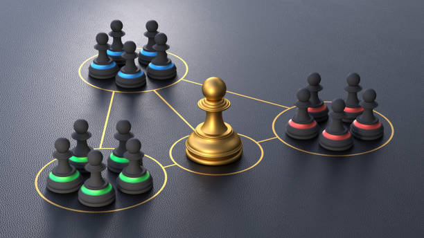 istock Leadership and team cohesiveness over black background. Three groups of chess pieces connected by arrows to the golden leader chess piece. 2162329794
