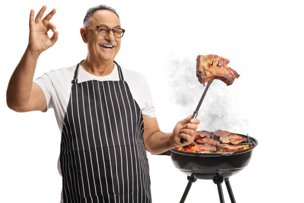 istock Man grilling meat on a barbecue and holding a steak on a fork 2162334582