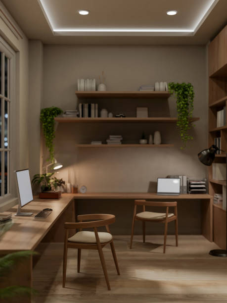 istock A cozy, contemporary workspace at night features a computer and a laptop on a wooden L-shaped table. 2162340962
