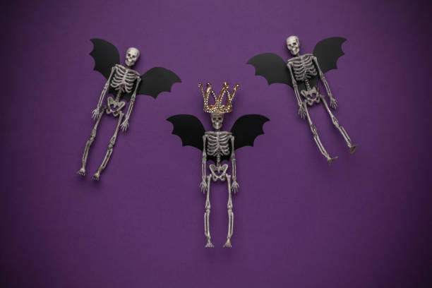 istock Halloween Skeleton Bats with Golden Crown on Purple Background 2162342765