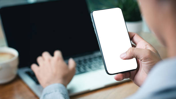 istock Mockup, man hands holding mobile phone with finger touching on blank screen. Man using smartphone, looking at the screen, overhead shot 2162347553