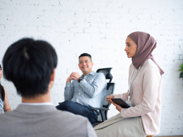 istock A diverse group of people sitting in a circle having a discussion in a modern, bright office space with a green plant in the background 2162353029