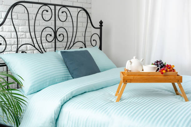 Decorative tray with book,tea set and flower on the bed