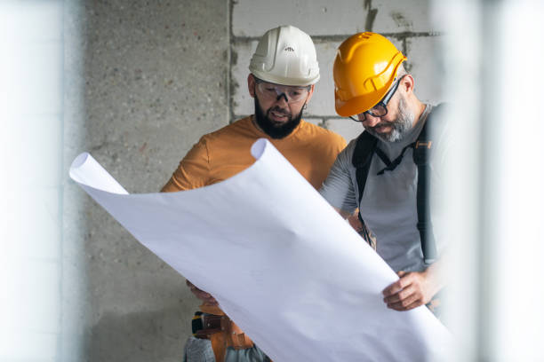 istock Two construction workers examining blueprints at in the house under construction 2162362027