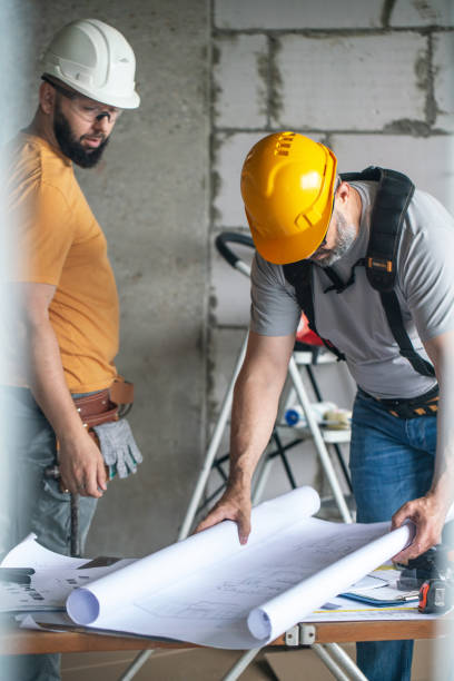 istock Two construction workers examining blueprints at in the house under construction 2162362039