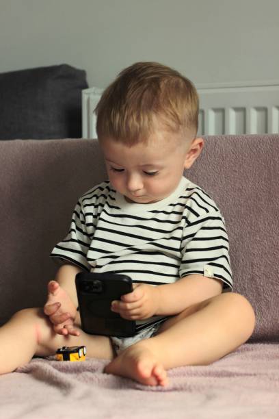 istock A small child is looking into the phone while sitting on the sofa 2162367422