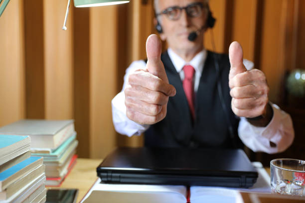 An elderly man in his office showing thumbs up