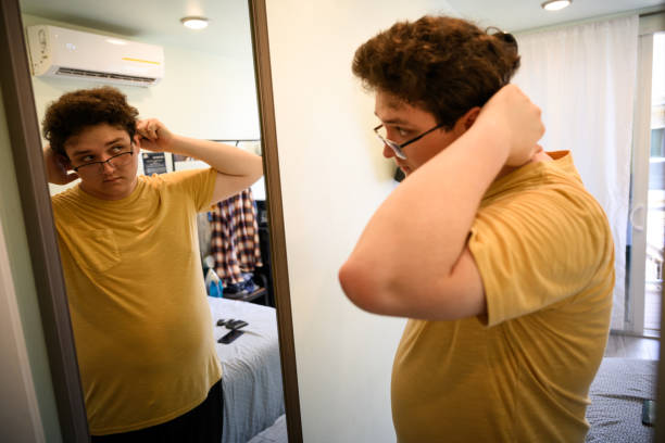 istock Young man getting ready brushing his hair looking in mirror 2162371310