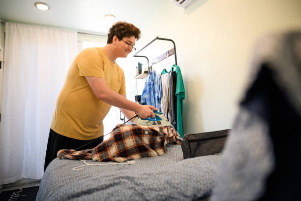 istock Happy Generation Z male ironing shirt on small ironing board in tiny home 2162371494