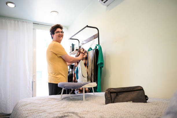 istock Candid shot young man hanging up his clothes in tiny home 2162371496