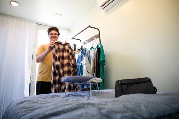 istock Happy young man preparing to iron clothes in tiny home on small ironing board 2162371497