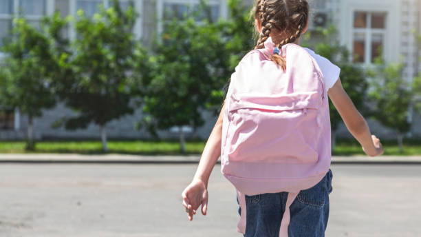 Little girl with backpack going to school, back view. Back to school. copy space