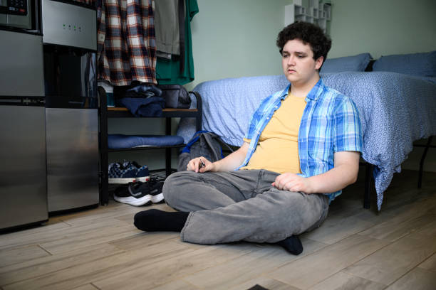 istock Young man depressed sitting cross-legged on floor in studio apartment 2162371656