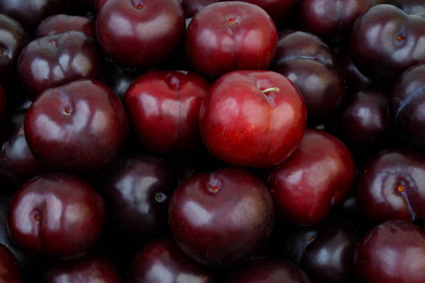 Close-Up Of Plums Sitting On Market Stall
