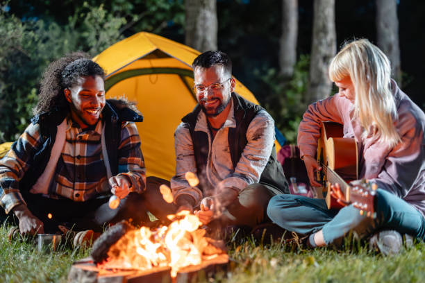istock Friends Roasting Marshmallows and Playing Guitar by Campfire 2162376433