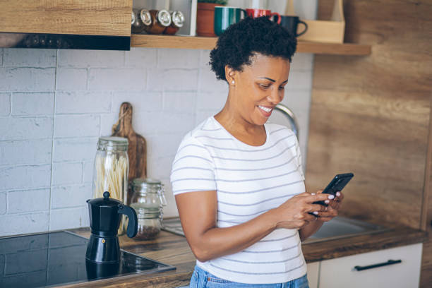 istock Woman uses a mobile phone while waiting for coffee to be made 2162378844