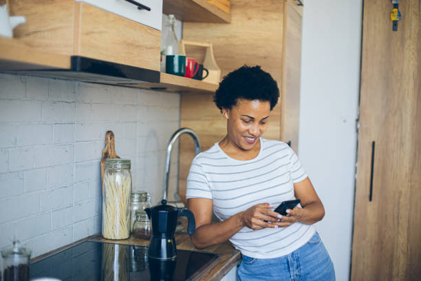 istock Woman uses a mobile phone while waiting for coffee to be made 2162378952