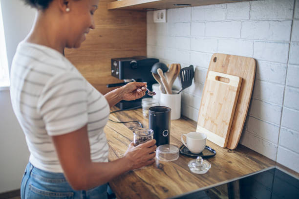 istock Beautiful smiling black woman making coffee in a domestic kitchen 2162379089