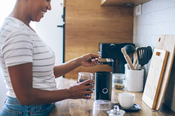 istock Beautiful smiling black woman making coffee in a domestic kitchen 2162379113