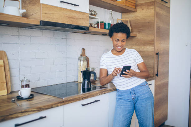 istock Woman uses a mobile phone while waiting for coffee to be made 2162379123