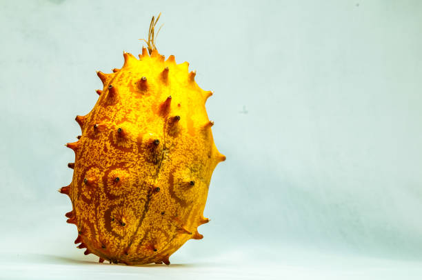 A large, yellow fruit with many spikes on it. The fruit is sitting on a white background