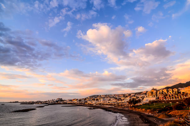 istock A beautiful beach scene with a cloudy sky and a small town in the background 2162380224