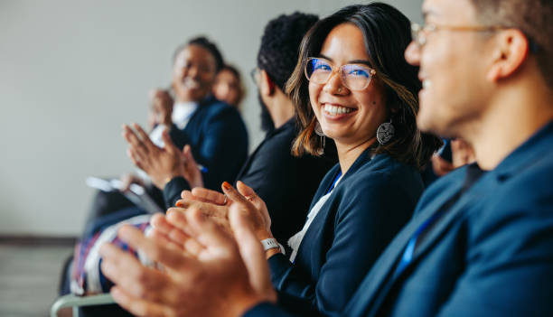 Group of diverse colleagues clapping and smiling happily during a business meeting, showcasing teamwork and positive workplace atmosphere.
