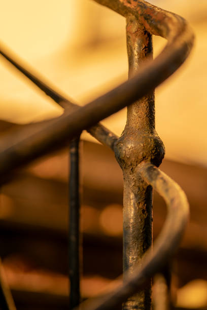 A close-up image of old, rusty black handrails with peeling paint. The texture of the rust and the worn metal show signs of age and weathering, capturing a sense of neglect and decay. The background is blurred, highlighting the handrails' details.