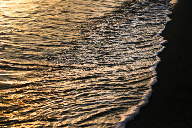 Waves drawing geometric shapes on the shore on the beach at sunset