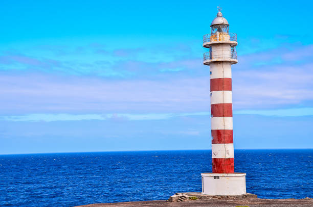 istock A lighthouse is on a rocky shoreline with a calm ocean in the background 2162385986