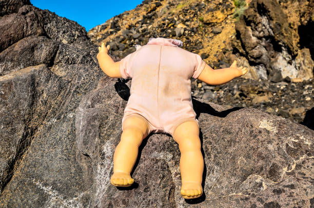 istock A doll's head is missing from its body and is sitting on a rock 2162386052