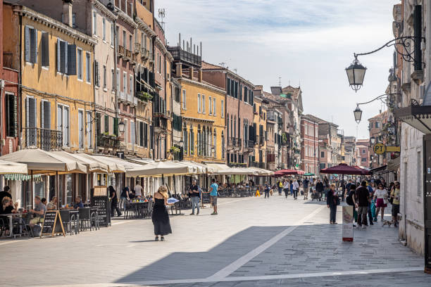 Venice, Italy - June 4th 2024:  One of the widest streets in Venice with outdoor restaurants and tourists enjoying the early summer sunlight in the center of the city