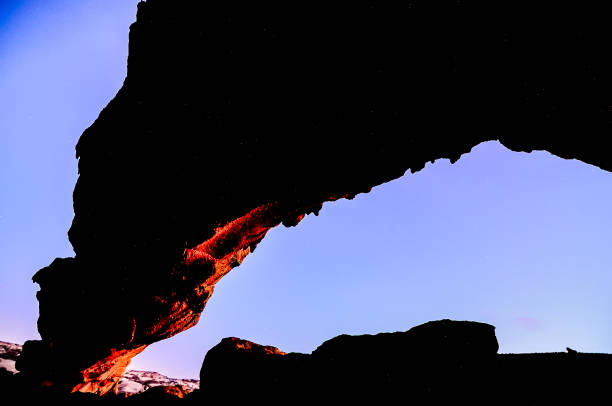 istock A rock formation with a hole in it and a dark sky above 2162393280