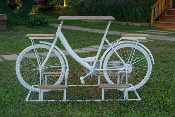 inventions to reduce global warming by bringing an old bicycle to design as a table with 2 seats in the middle as a table Placed on the lawn. Soft and selective focus.