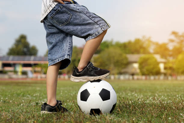 istock Asian boy stepping on a ball while kicking soccer on the field. soft and selective focus. 2162398471
