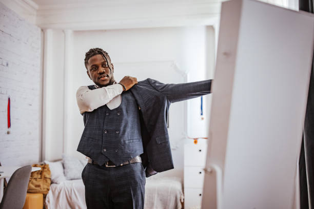 Man putting on suit jacket in modern bedroom