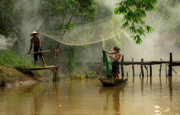 istock Two farmers on a boat in the river using a fishnet to catch fish 2162402593