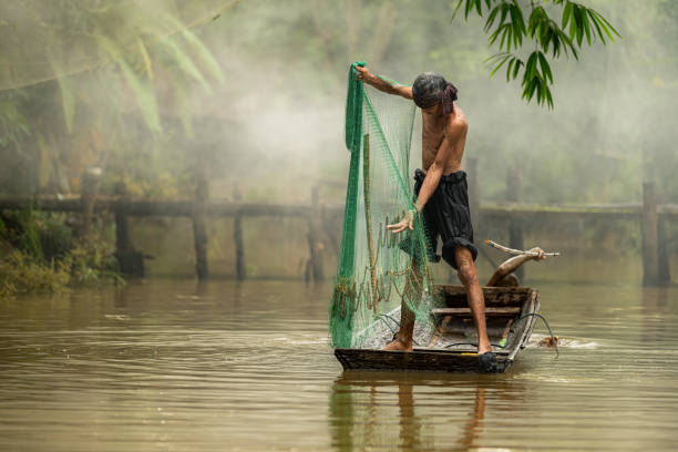 istock Two farmers on a boat in the river using a fishnet to catch fish 2162402760